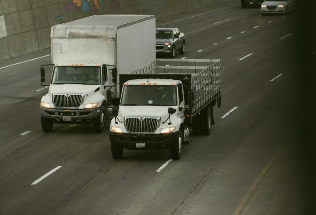 Two white trucks driving on a highway