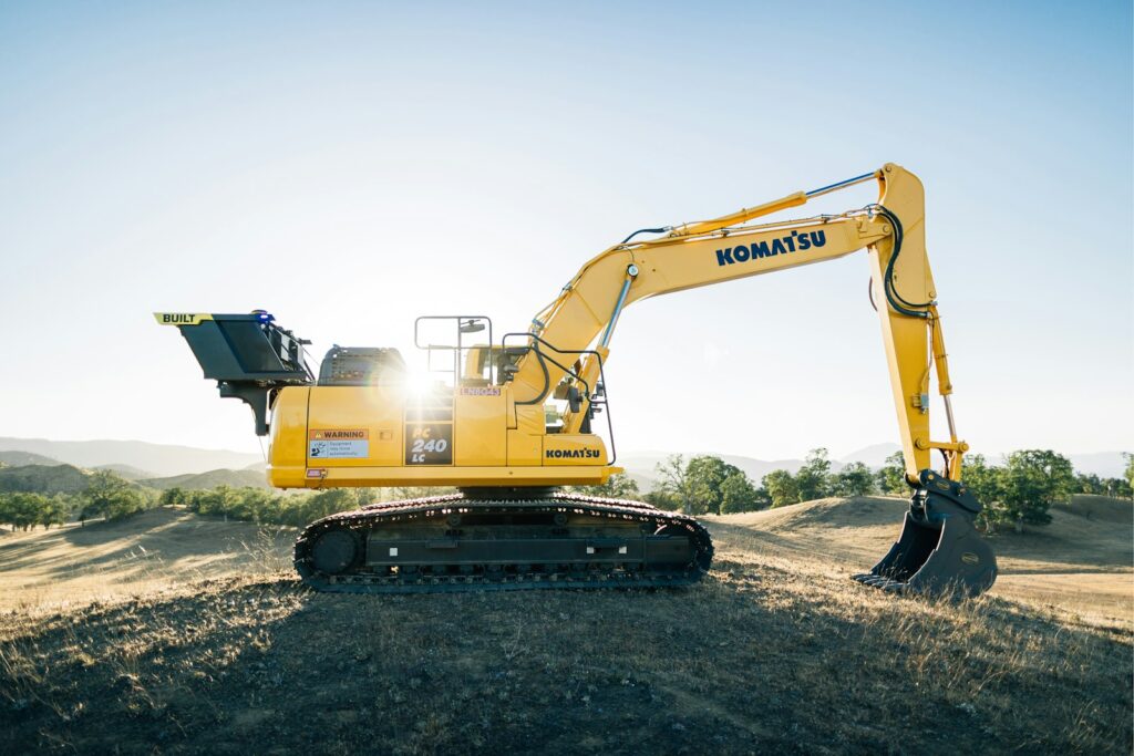 A yellow excavator sitting on top of a dirt field