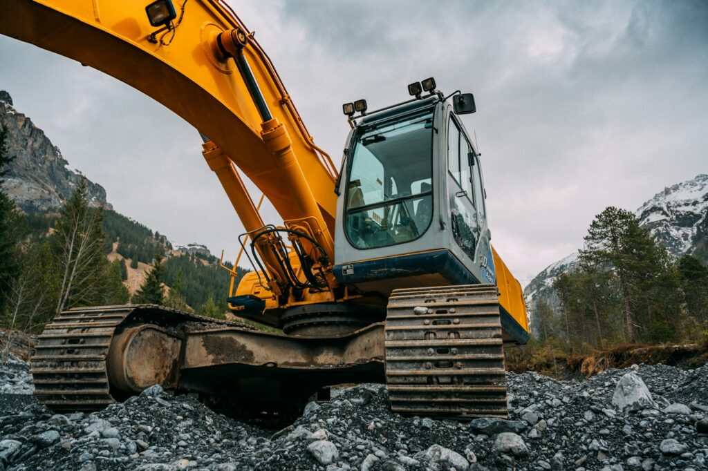 Yellow and green excavator on rocky ground during daytime