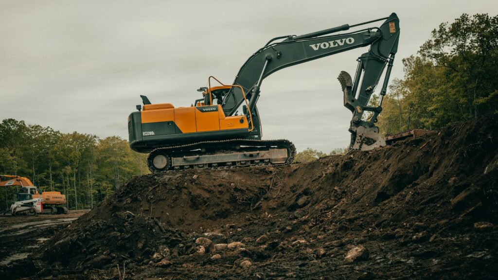 Orange and white excavator on brown ground during daytime