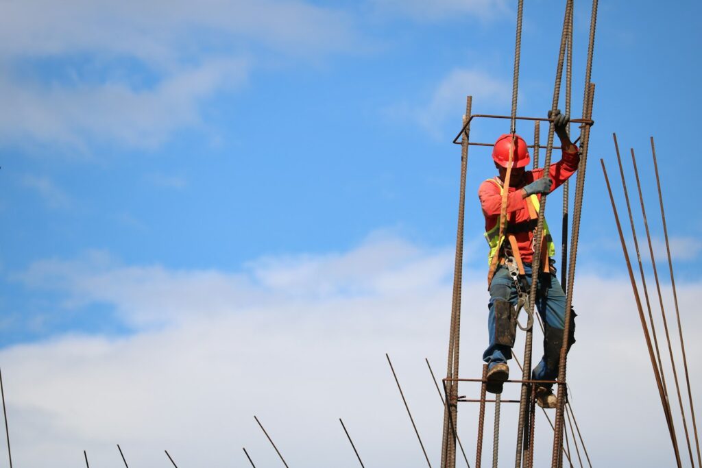 Man wearing red hard hat hanged on brown rebar bar