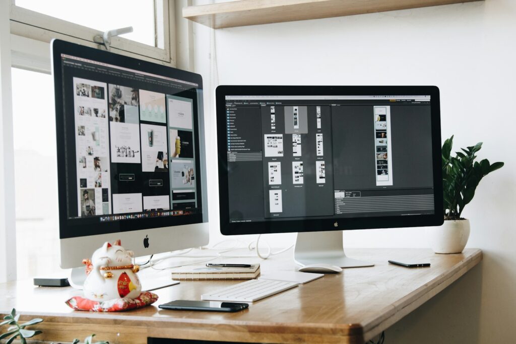 Two computer monitors sitting on top of a wooden desk