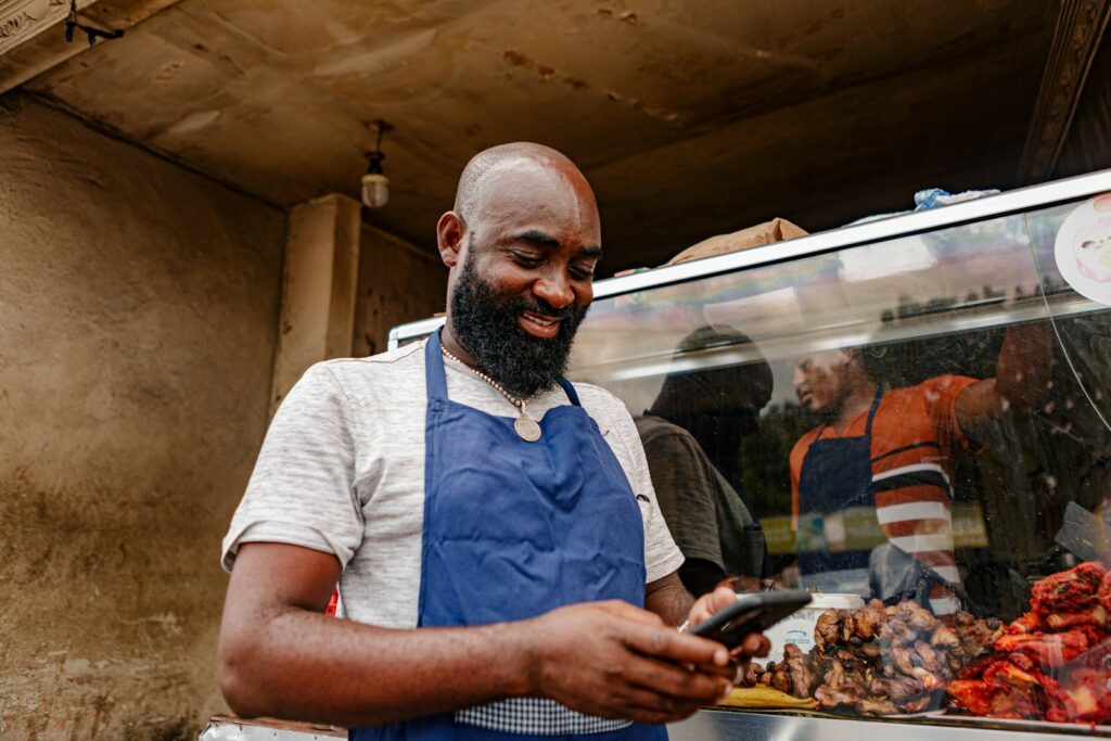 A man in an apron looking at a cell phone